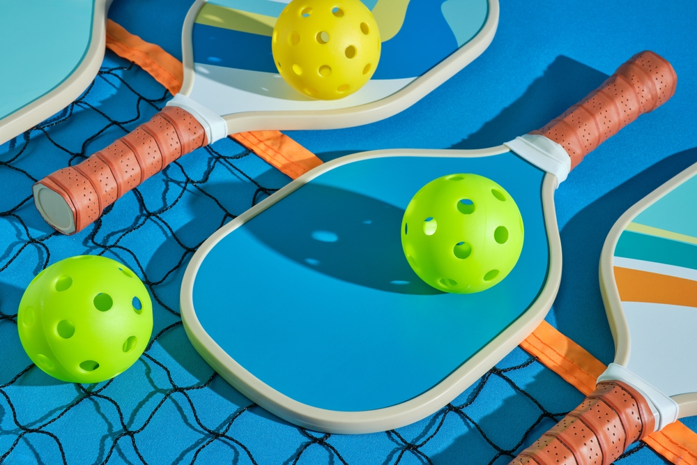 Pickleball,paddles,with,balls,on,top,of,a,net,on