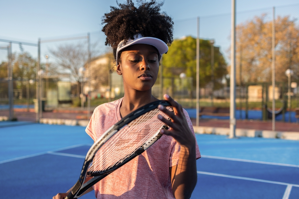 Concentrating,female,tennis,player,checking,the,tension,of,her,racket